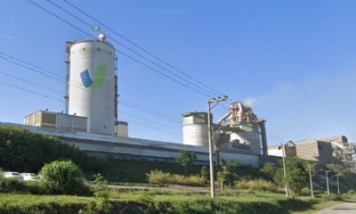 Industrial plant with a tall white silo and processing buildings under a clear blue sky
