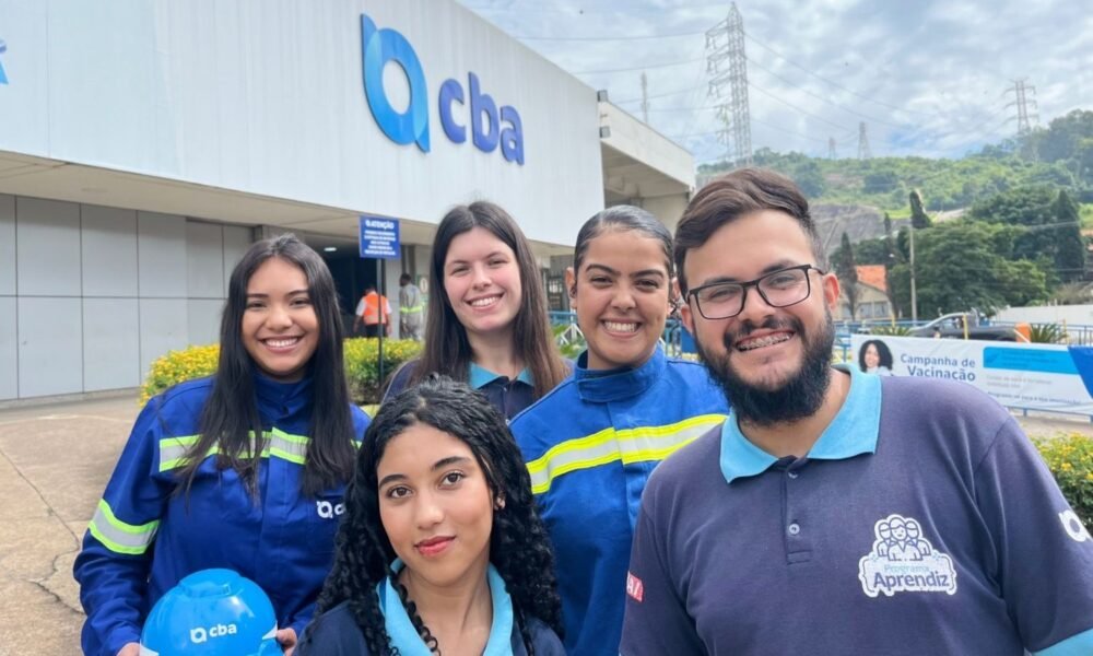 Group of five volunteers in blue uniforms pose outside a building with a CBA sign, smiling for the photo during a vaccination campaign.",