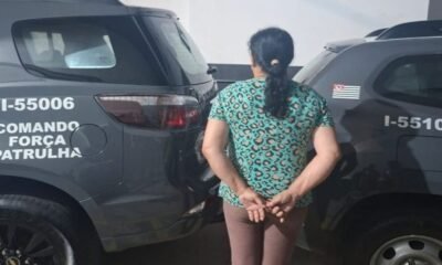 Woman in a teal leopard print shirt stands with hands behind her back between two dark gray patrol SUVs