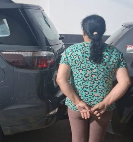 Woman in a teal leopard print shirt stands with hands behind her back between two dark gray patrol SUVs