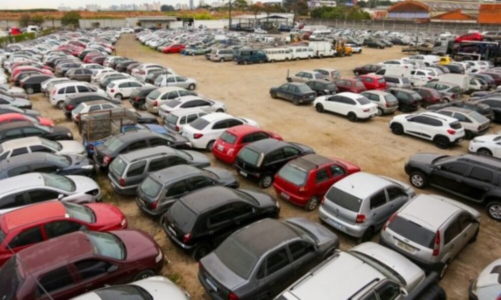 Aerial view of a vast dirt parking lot filled with rows of cars in various colors and sizes stretching into the distance