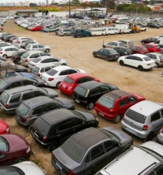 Aerial view of a vast dirt parking lot filled with rows of cars in various colors and sizes stretching into the distance