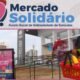 Banner for Mercado Solidário fundraiser cheerful woman with a grocery basket of vegetables and a thumbs up outside a community center logo text Mercado Solidário at top