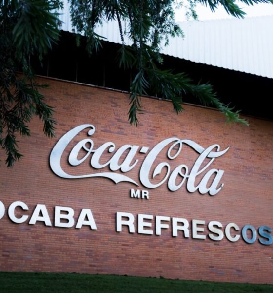 Brick wall with a large Coca Cola logo and the words SOROCABA REFRESCOS SA under it with overhanging tree branches