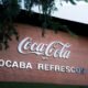 Brick wall with a large Coca Cola logo and the words SOROCABA REFRESCOS SA under it with overhanging tree branches