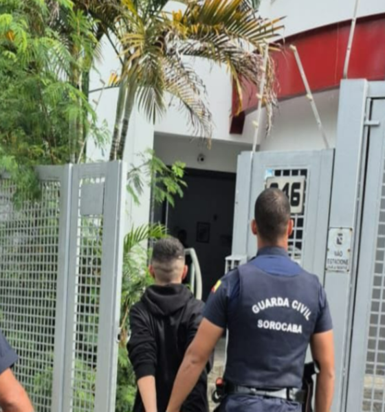 Two Guarda Civil Sorocaba officers escort a man toward a gated entrance