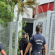 Two Guarda Civil Sorocaba officers escort a man toward a gated entrance