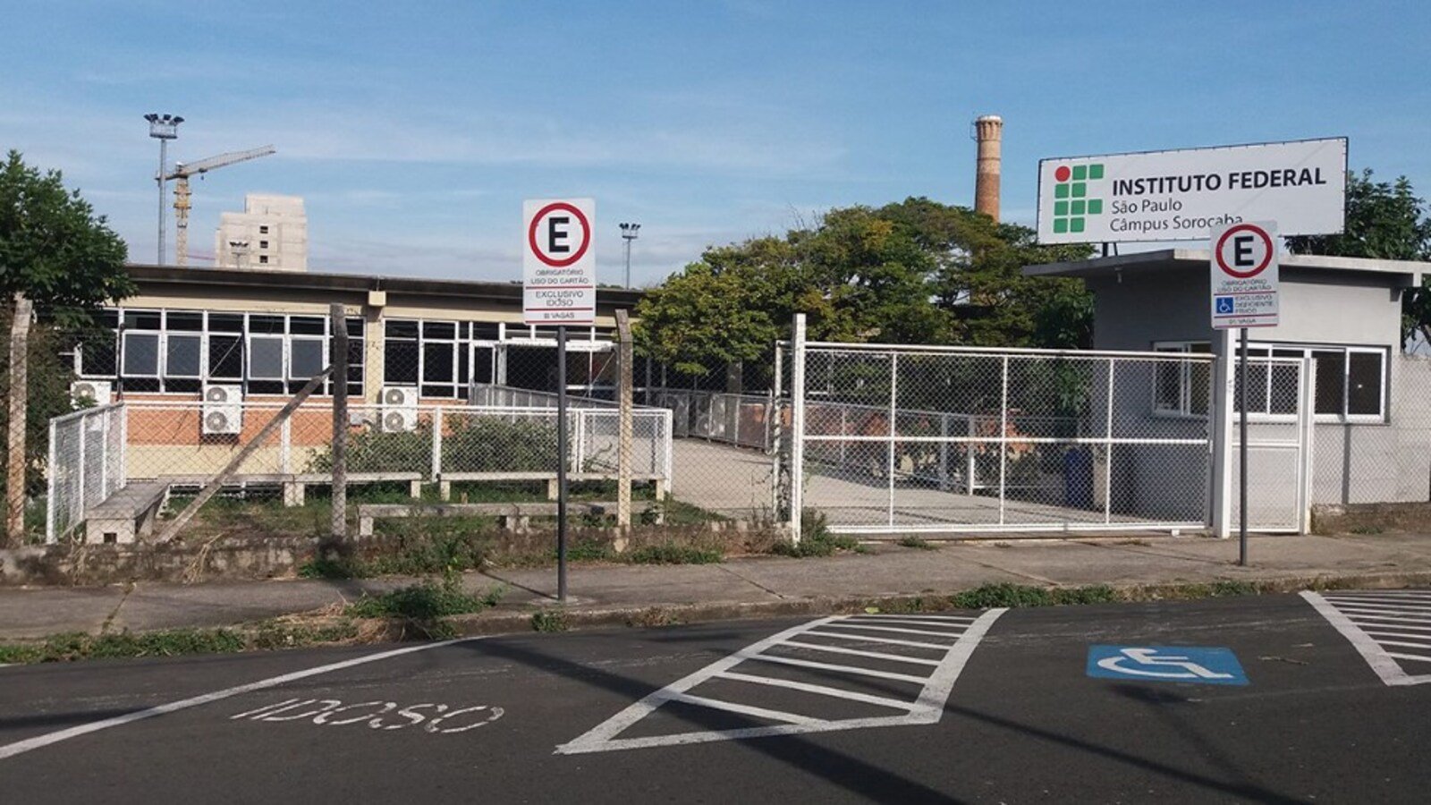 Entrance to Instituto Federal São Paulo campus Sorocaba with a gated fence and a handicap parking space marked on the pavement fringing a blue and white symbol wheelchair