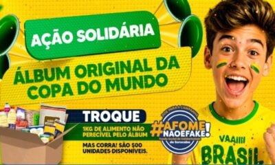 Jovem brasileiro com camiseta amarela e rosto pintado vibra ao lado de uma caixa de alimentos para uma ação solidária da Copa do Mundo