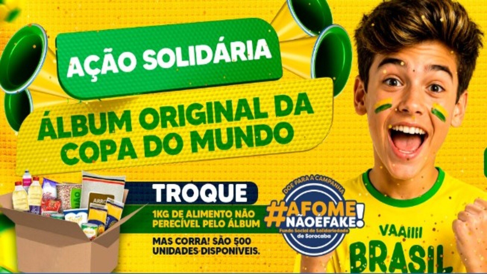 Jovem brasileiro com camiseta amarela e rosto pintado vibra ao lado de uma caixa de alimentos para uma ação solidária da Copa do Mundo