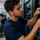 Male technician in a blue shirt cables a network rack in a data center