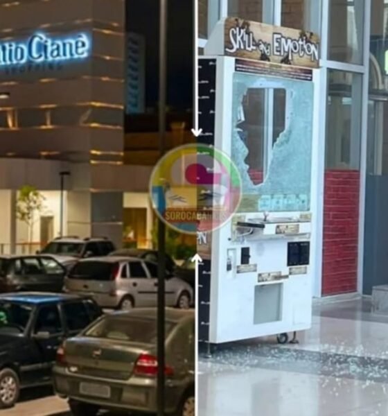 Night scene of a parking lot filled with cars with a lit building sign Patio Crane in the background and on the right a storefront with a shattered glass window and a vending machine inside the display area