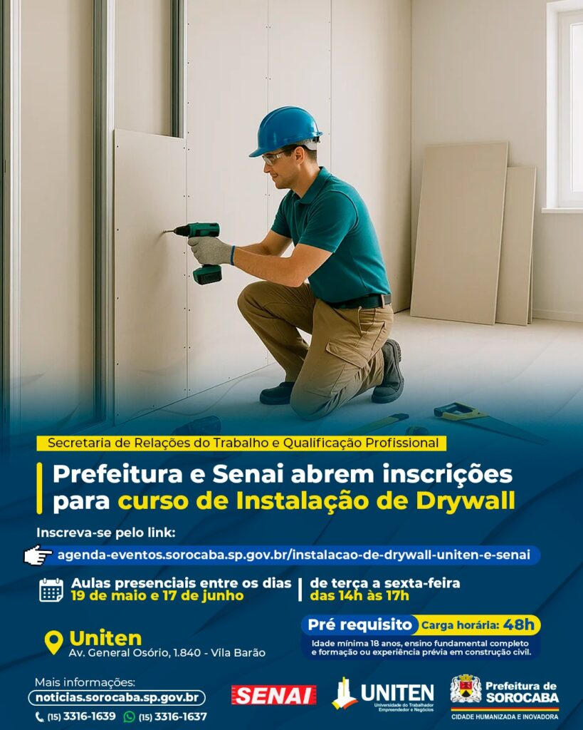 Construction worker in a teal shirt and blue hard hat kneels drilling drywall panels inside a room a blue ad banner overlays the bottom with Portuguese text about a drywall installation course and city logos