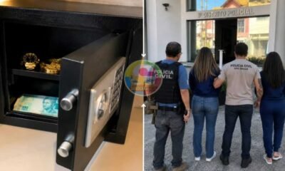 Open safe displaying cash and gold watches outside people stand near a São Paulo Civil Police station entrance