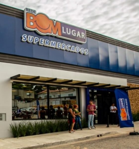 Exterior of Bom Lugar Supermercados storefront with blue panels and glass entrance people standing outside under an awning
