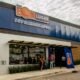 Exterior of Bom Lugar Supermercados storefront with blue panels and glass entrance people standing outside under an awning