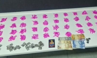 Row of bright pink paper shapes spread on a table with stacks of banknotes coins and a small emblemcrest nearby