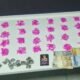 Row of bright pink paper shapes spread on a table with stacks of banknotes coins and a small emblemcrest nearby