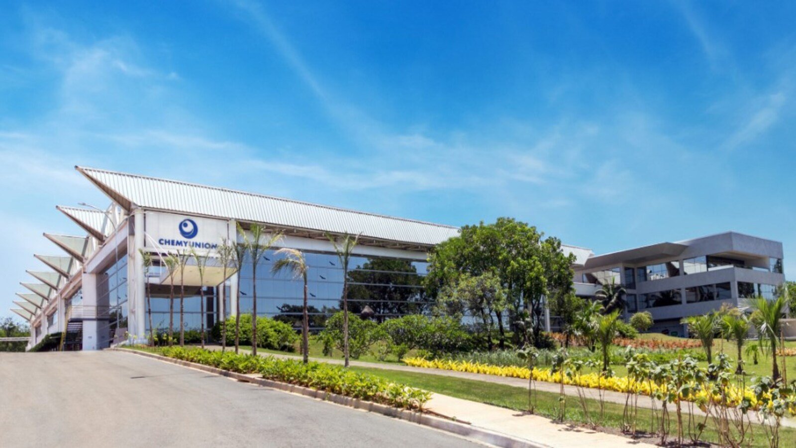 Modern glass front corporate building with ChemyUnion sign surrounded by palm trees on a sunny day