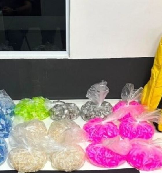 Colorful bags of small snacks in plastic wrap arranged on a white counter beside a yellow delivery bag labeled Pede  Food and a phone