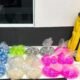 Colorful bags of small snacks in plastic wrap arranged on a white counter beside a yellow delivery bag labeled Pede  Food and a phone