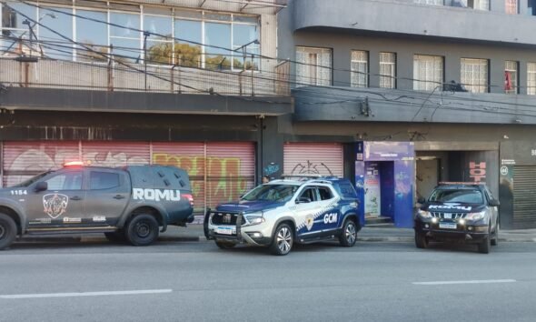 Three police vehicles parked along a city street in front of graffiti covered storefronts left a gray ROMU pickup center a white and blue GCM SUV right a dark ROMU SUV