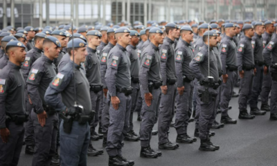Line of uniformed officers standing at attention in a parade formation in gray uniforms with patches on sleeves