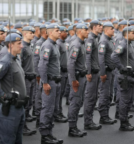 Line of uniformed officers standing at attention in a parade formation in gray uniforms with patches on sleeves