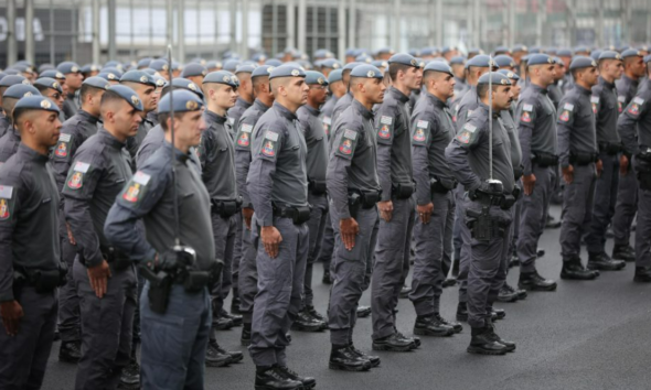 Line of uniformed officers standing at attention in a parade formation in gray uniforms with patches on sleeves
