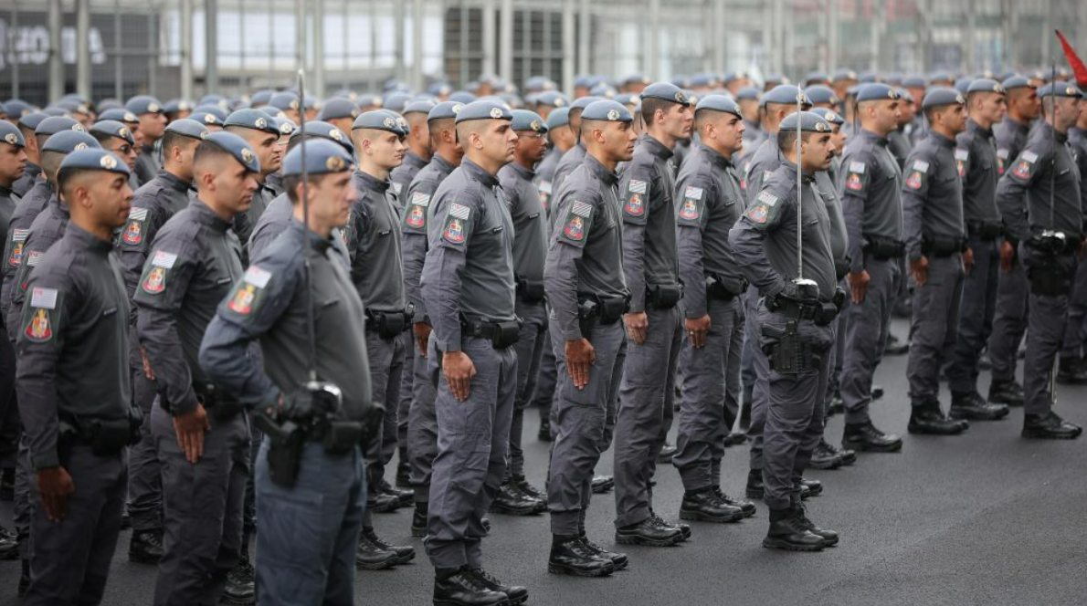 Line of uniformed officers standing at attention in a parade formation in gray uniforms with patches on sleeves