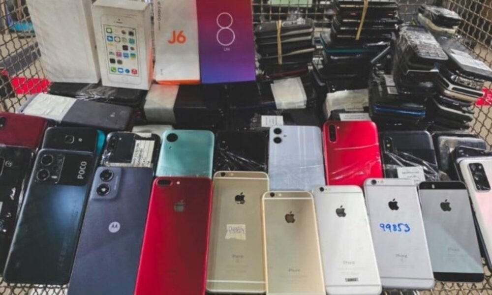 Cart overflowing with dozens of smartphones, backs facing up in various colors and models, likely second-hand devices for sale.
