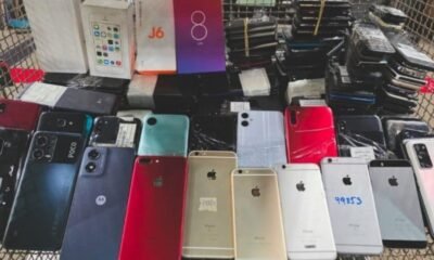 Cart overflowing with dozens of smartphones backs facing up in various colors and models likely second hand devices for sale