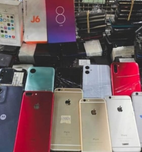 Cart overflowing with dozens of smartphones backs facing up in various colors and models likely second hand devices for sale