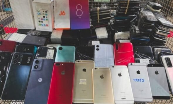 Cart overflowing with dozens of smartphones backs facing up in various colors and models likely second hand devices for sale