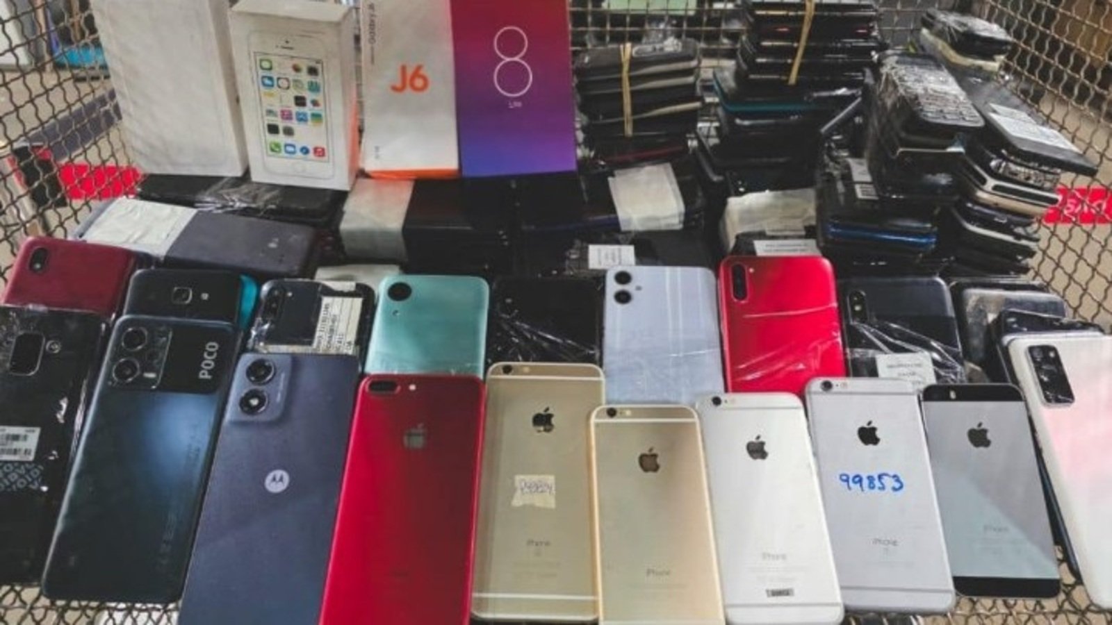 Cart overflowing with dozens of smartphones backs facing up in various colors and models likely second hand devices for sale