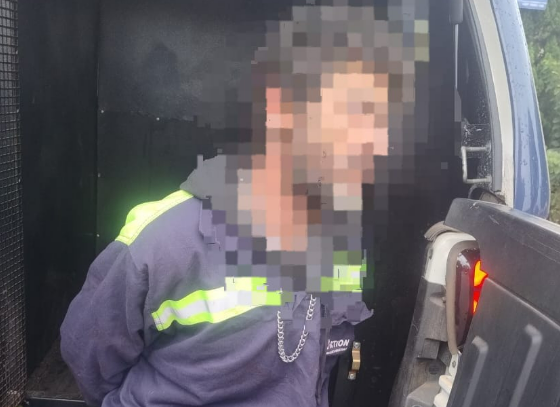 Man wearing a dark jacket with neon reflective stripes leaning into an open van a hand near the tailgate edge