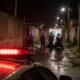 Nighttime alley scene with police and medics near an ambulance red emergency lights reflect on the wet street in the foreground