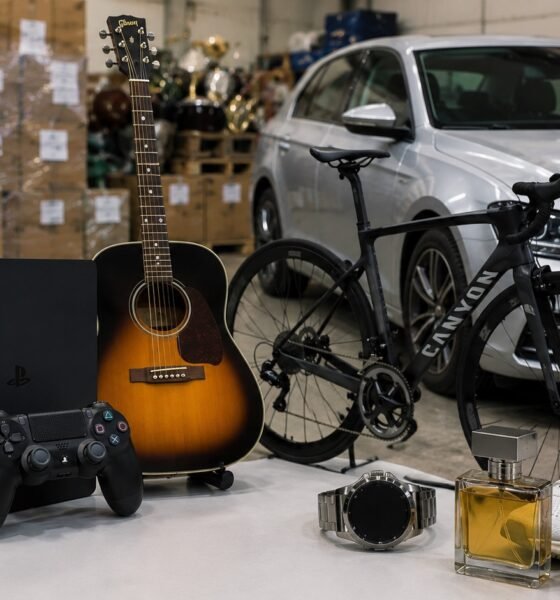 Assorted consumer goods on a table in a warehouse iPhone box PS guitar Canyon bike sneakers watch and perfume