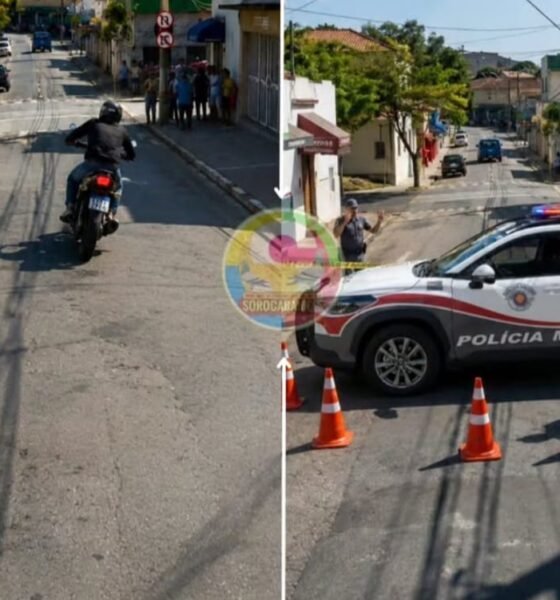 Urban street police checkpoint a Polícia Militar officer on foot and a motorcyclist stopped ahead with a patrol car blocking the road and traffic cones lined up