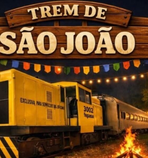 Wooden sign reading Trem de São João above a festive night scene with a yellow train car string lights and market stalls in the background