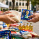 Two people exchange a bag of rice for FIFA  promotional cards at an outdoor market or charity stall with food supplies in the foreground