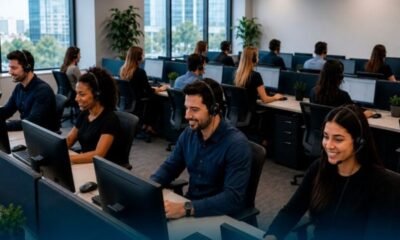 Open plan call center with agents wearing headsets at computer workstations and desks