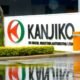 Industrial facility entrance with a white sign reading KANJIKO and a red green circular logo wet pavement reflects the sign