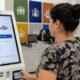 Woman using a govbr self service kiosk at a counter in a government office card in hand intake screen visible