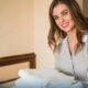 Smiling hotel housekeeper folds towels on a bed in a cozy room ready for a guest stay