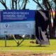 Billboard advertising a roadworks project in Portuguese mounted on a metal frame with a black cloth covering the right side