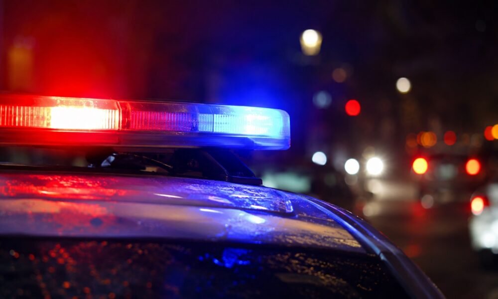 Police car with red and blue emergency lights flashing at night.