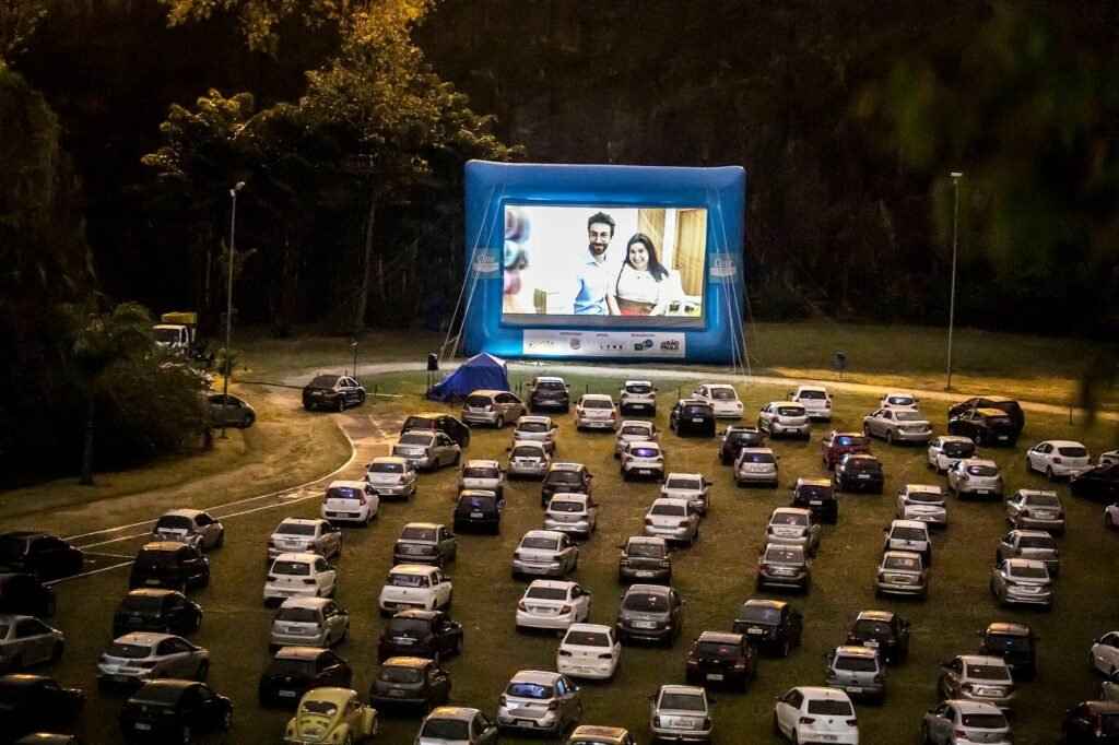 Cine autorama campinas por danilo ramos sorocabanices Nighttime drive in cinema with rows of cars parked on a grassy field facing a large inflatable screen showing a couple on screen