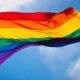 Rainbow Pride flag waving against a blue sky symbolizing LGBTQ pride and diversity
