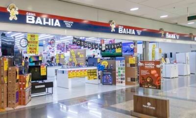 Bright electronics store inside a mall with stacked boxes yellow sale signs and checkout counters in the background